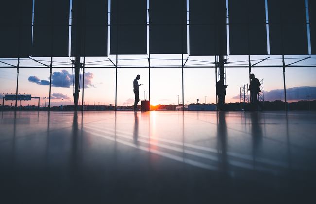 Three people standing in an airport as the sun rises in the distance
