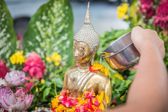Locals pour water over Buddha statues as a Songkran tradition of purification