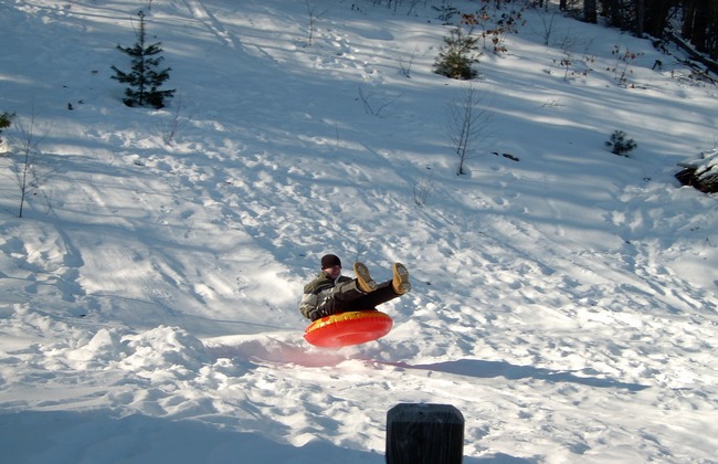 A person snow tubing down a snowy hill